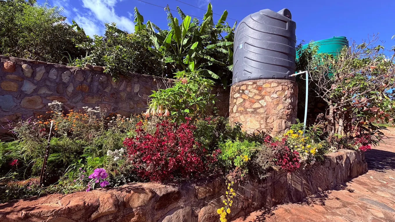 Terraced flower gardens at Eland Mountain Lodge with backup water storage tanks on stone plinths